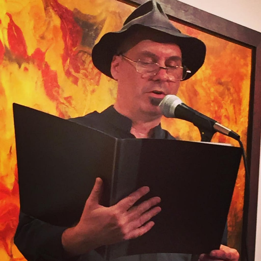 Scoddy with reading galsses at a poetry night.
